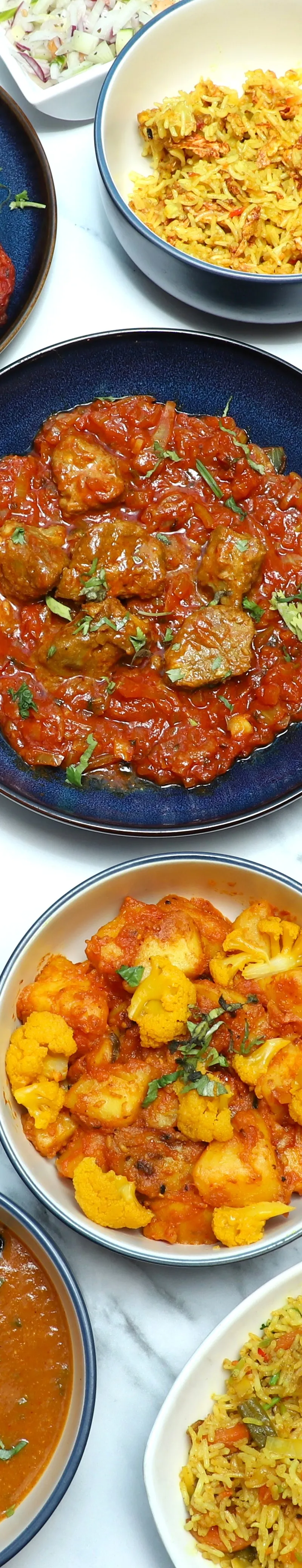 An overhead shot of various colourful Indian dishes in blue and white bowls, with rice, curry, naan, and chutneys.