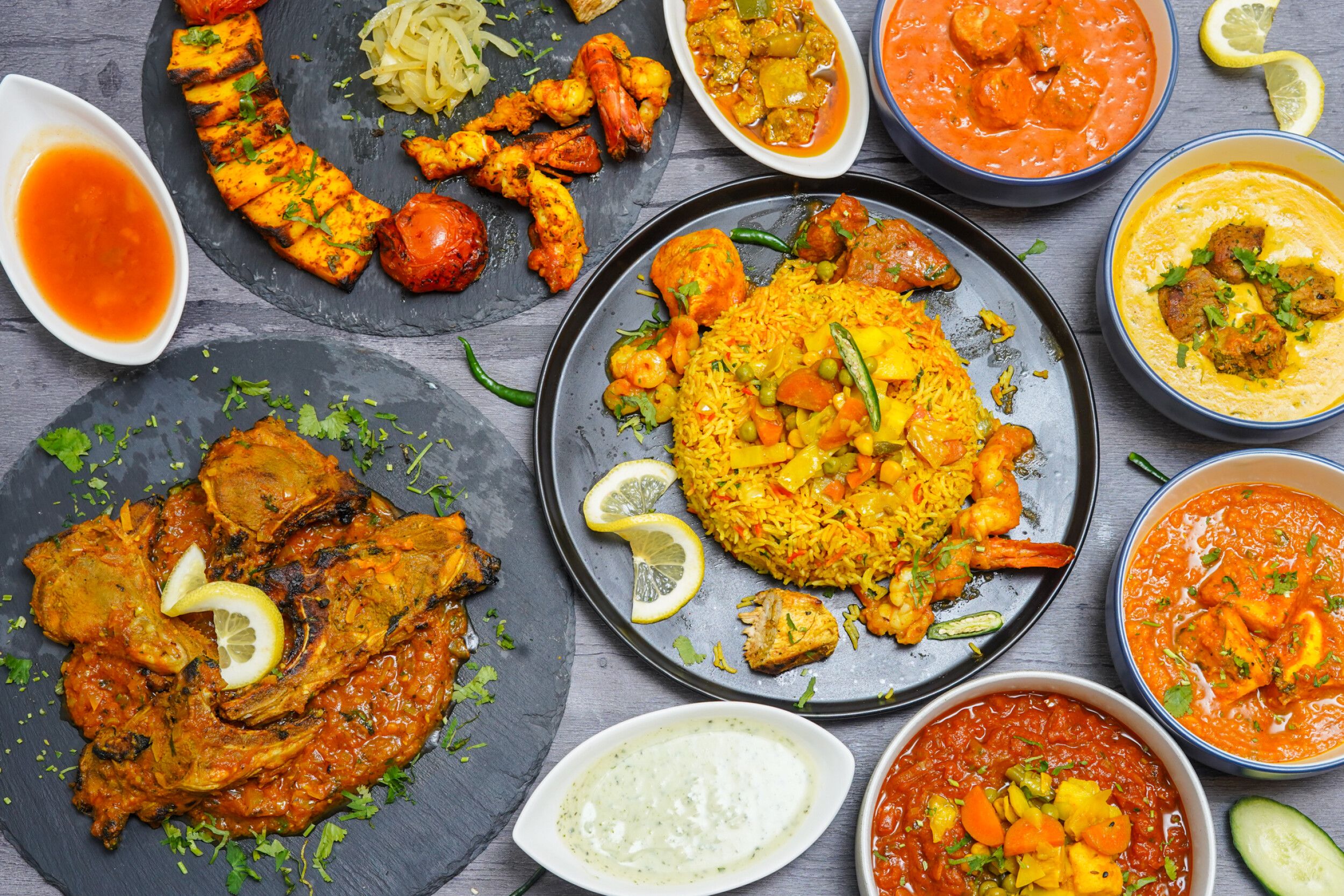 A variety of Indian halal dishes including curries, rice, lamb chops, prawns, and paneer tikka.