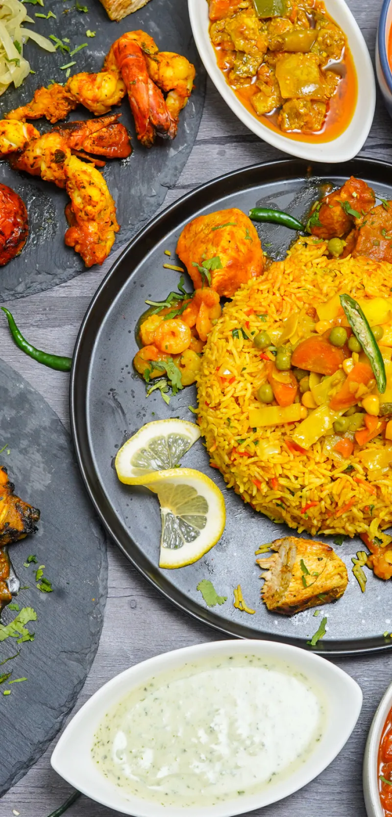 A variety of Indian halal dishes including curries, rice, lamb chops, prawns, and paneer tikka.