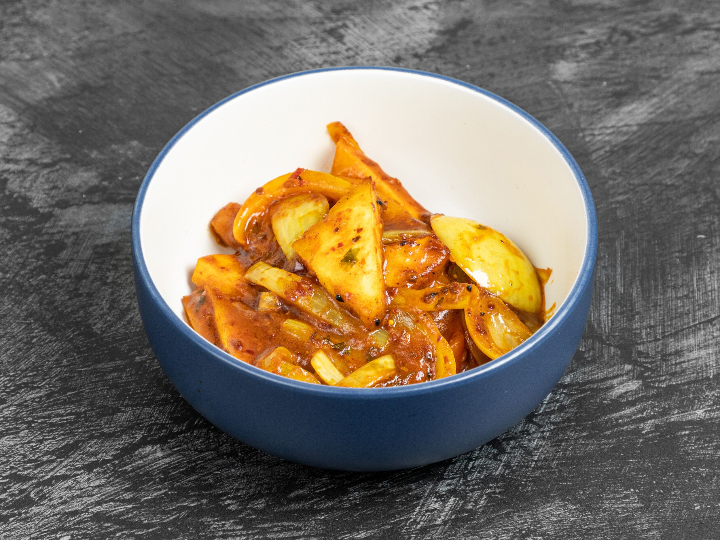 A close-up of a blue and white ceramic bowl filled with cooked pineapple curry.