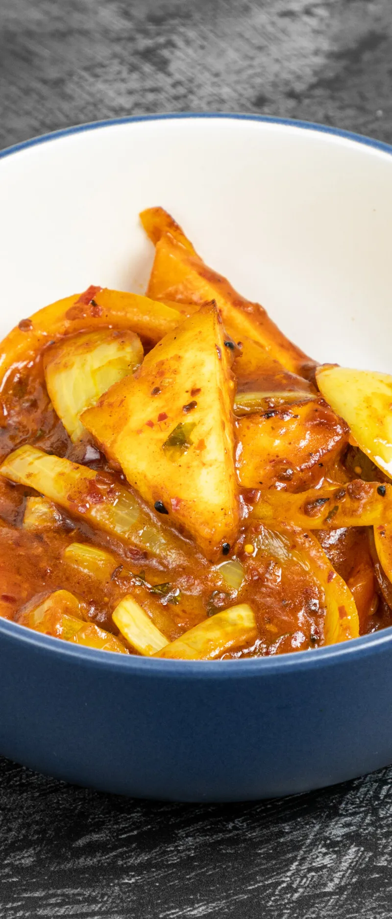 A close-up of a blue and white ceramic bowl filled with cooked pineapple curry.