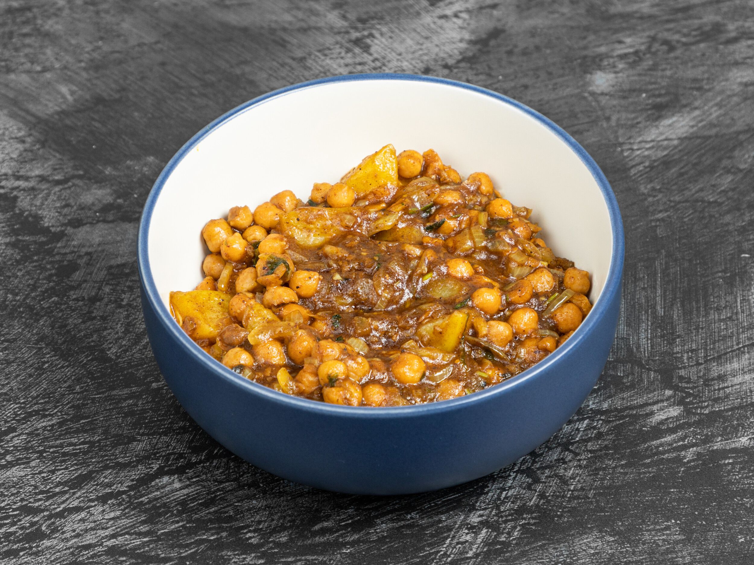 Chana Aloo, a chickpea and potato curry, in a blue and white ceramic bowl