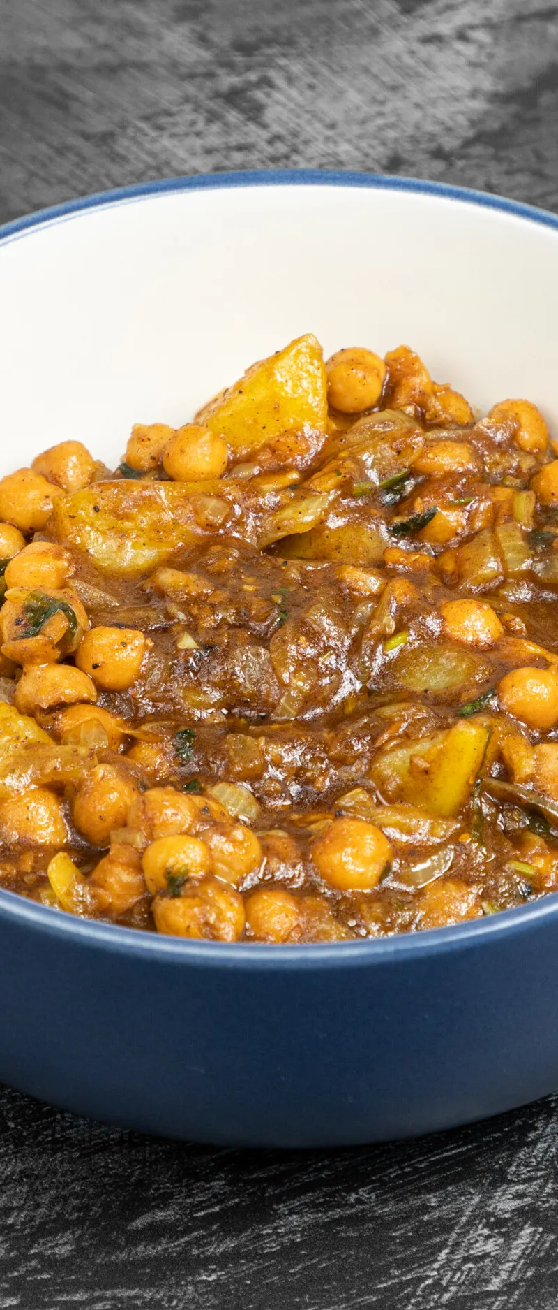 Chana Aloo, a chickpea and potato curry, in a blue and white ceramic bowl