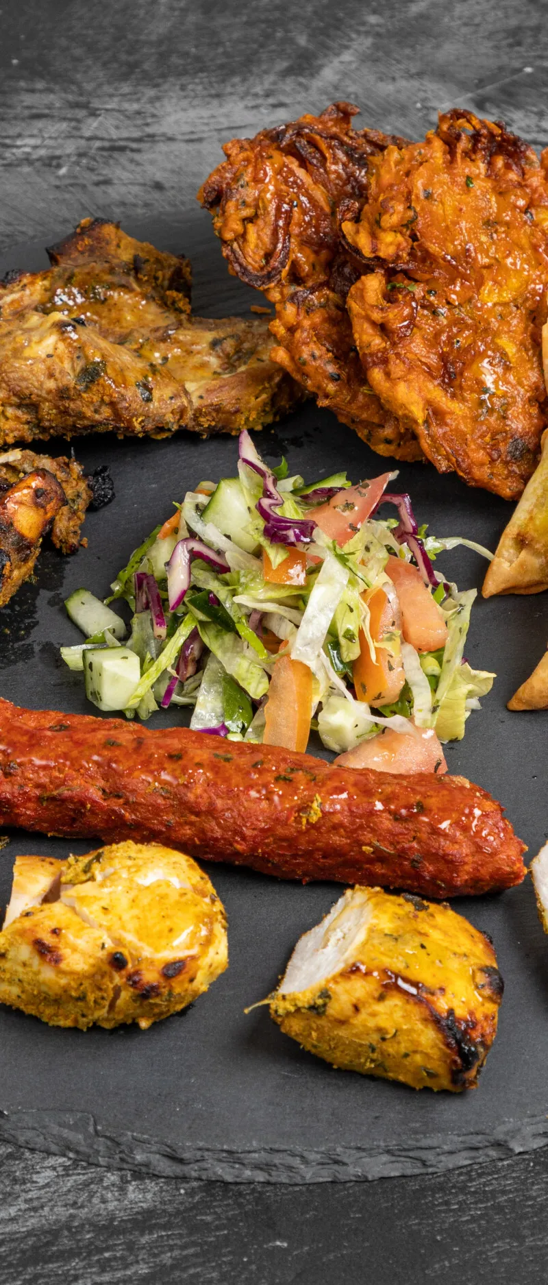 Mixed platter with lamb chops, onion bhajis, vegetable samosas, seekh kebab, chicken tikka, and salad