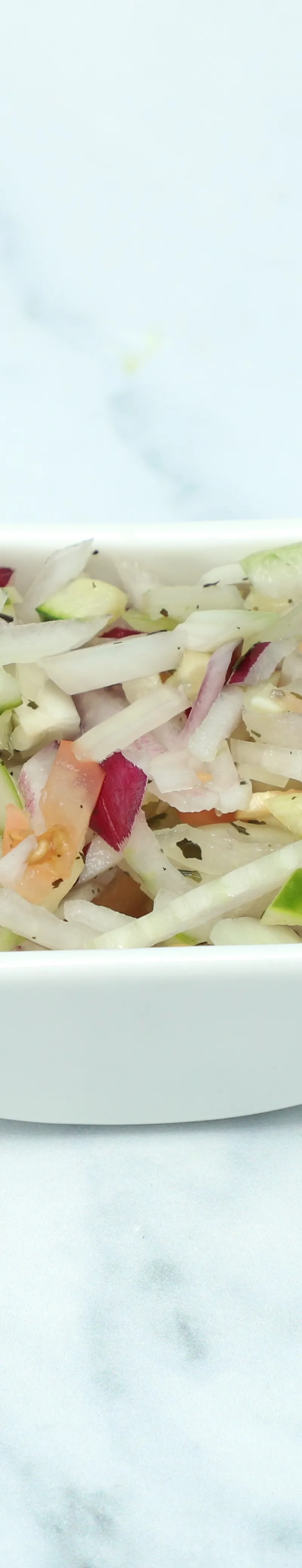 A small white bowl filled with diced red onion, white onion, cucumber, and orange red pepper.