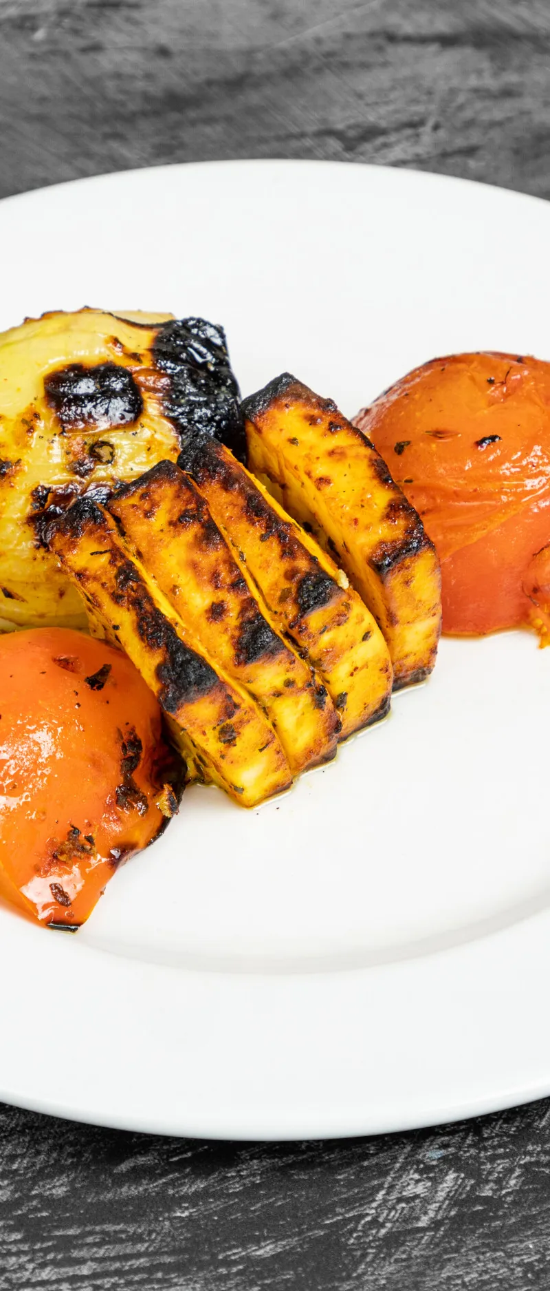 Grilled paneer slices, onion, red bell pepper, and tomato on a white plate