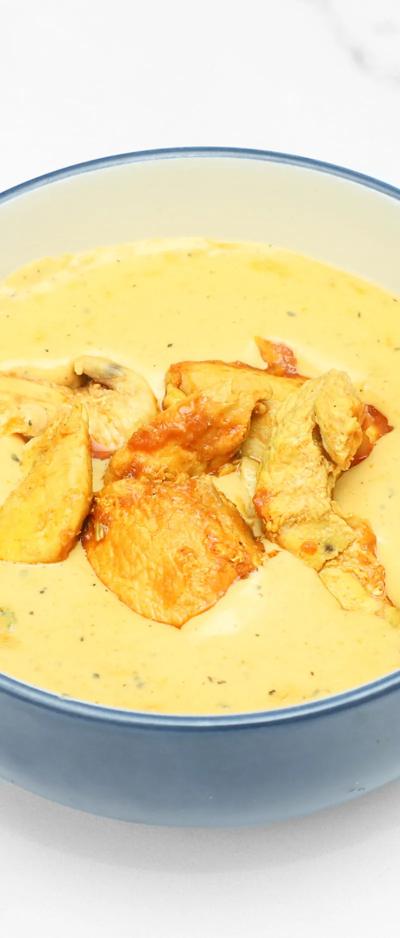 Tender pieces of chicken in a rich, creamy yellow curry, served in a blue bowl
