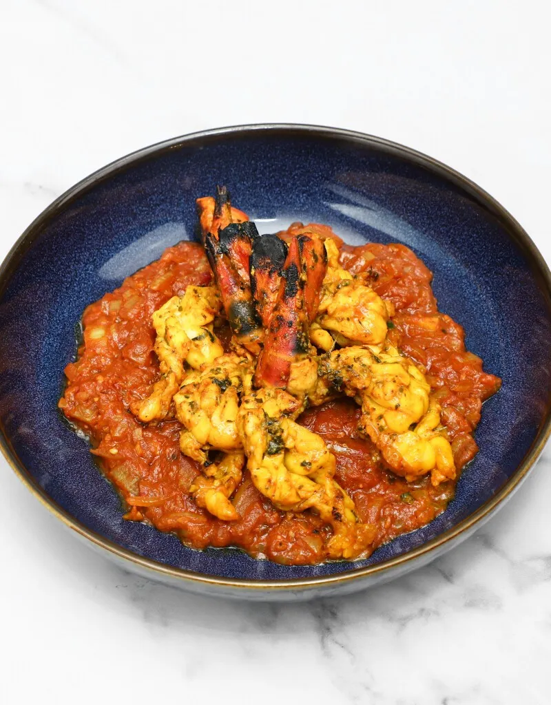 Grilled jumbo prawns and smaller prawns on a bed of sauteed tomatoes and onion sauce.