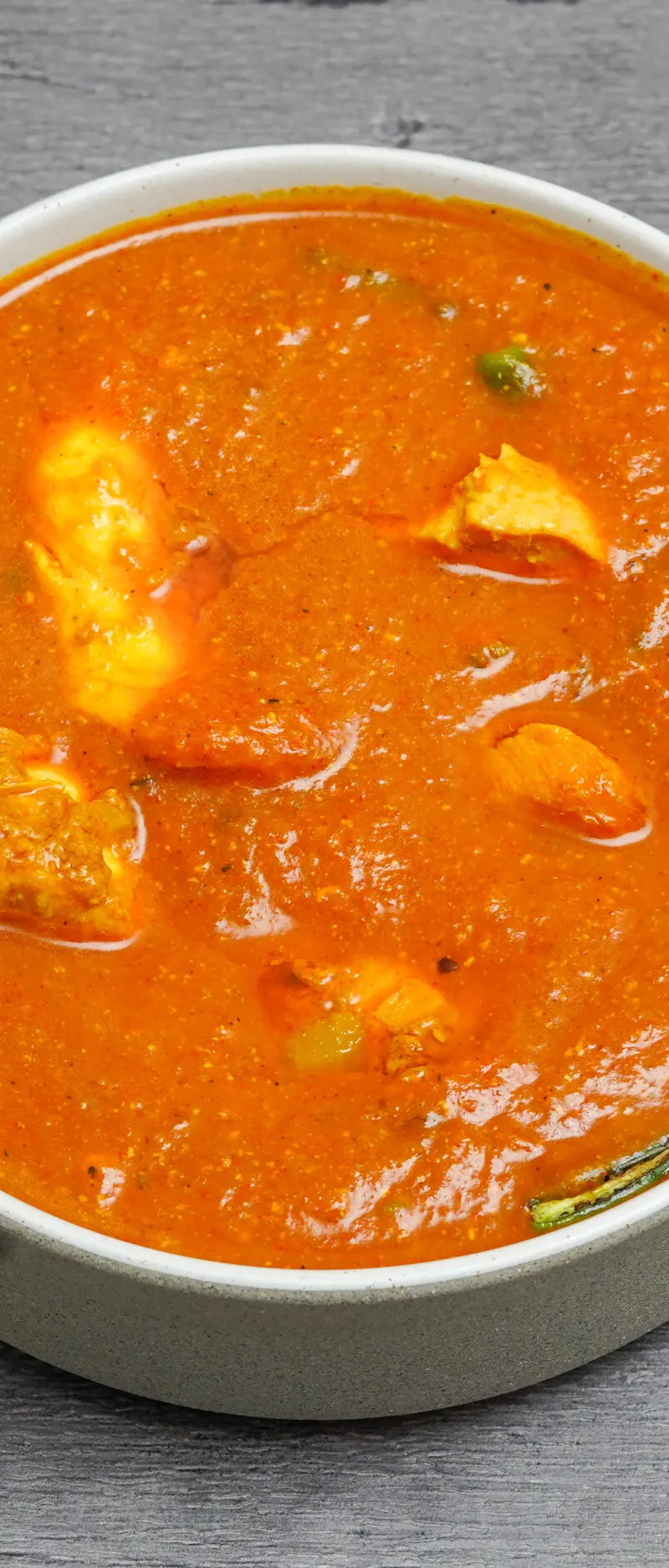 Chicken tikka masala curry in a white serving bowl with rich orange sauce and chicken pieces.