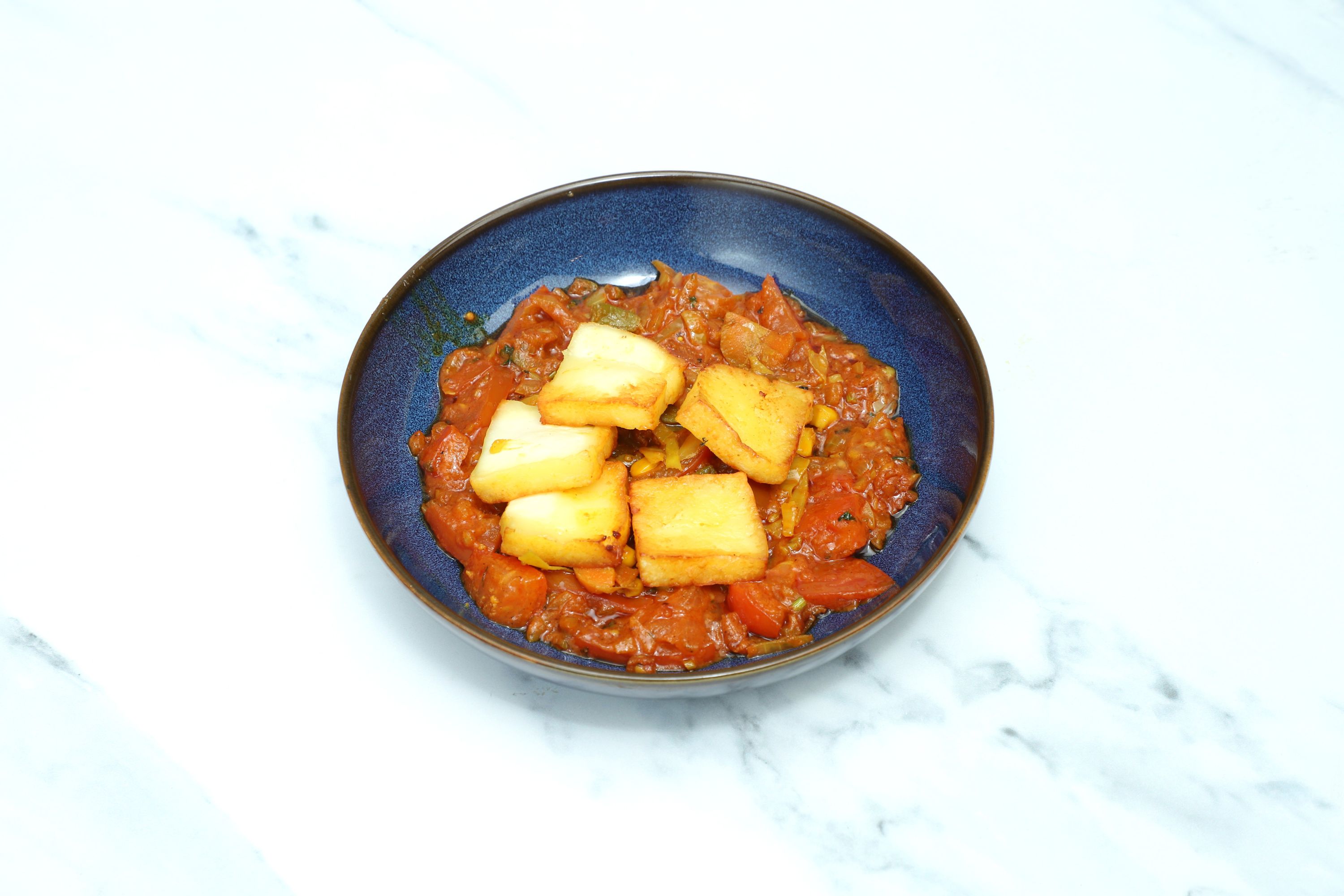 Four golden fried paneer slices sit atop a dish of chilli paneer with mixed vegetables.