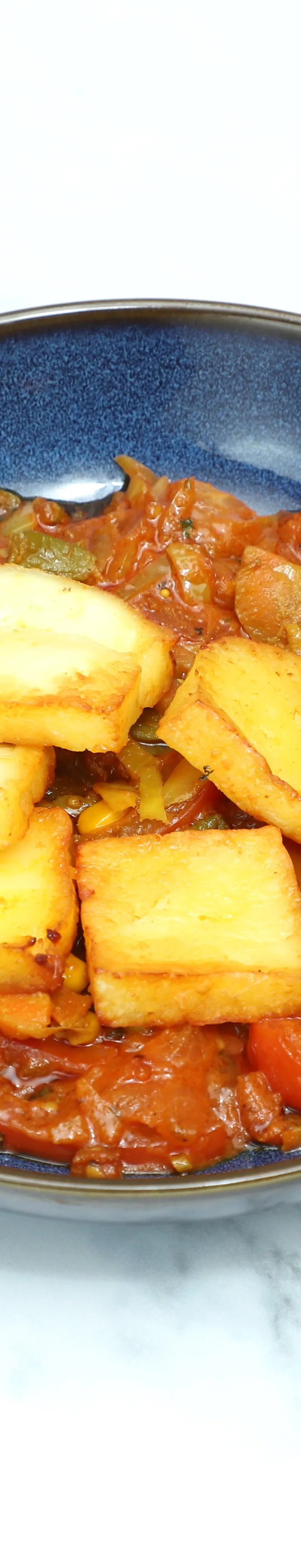 Four golden fried paneer slices sit atop a dish of chilli paneer with mixed vegetables.