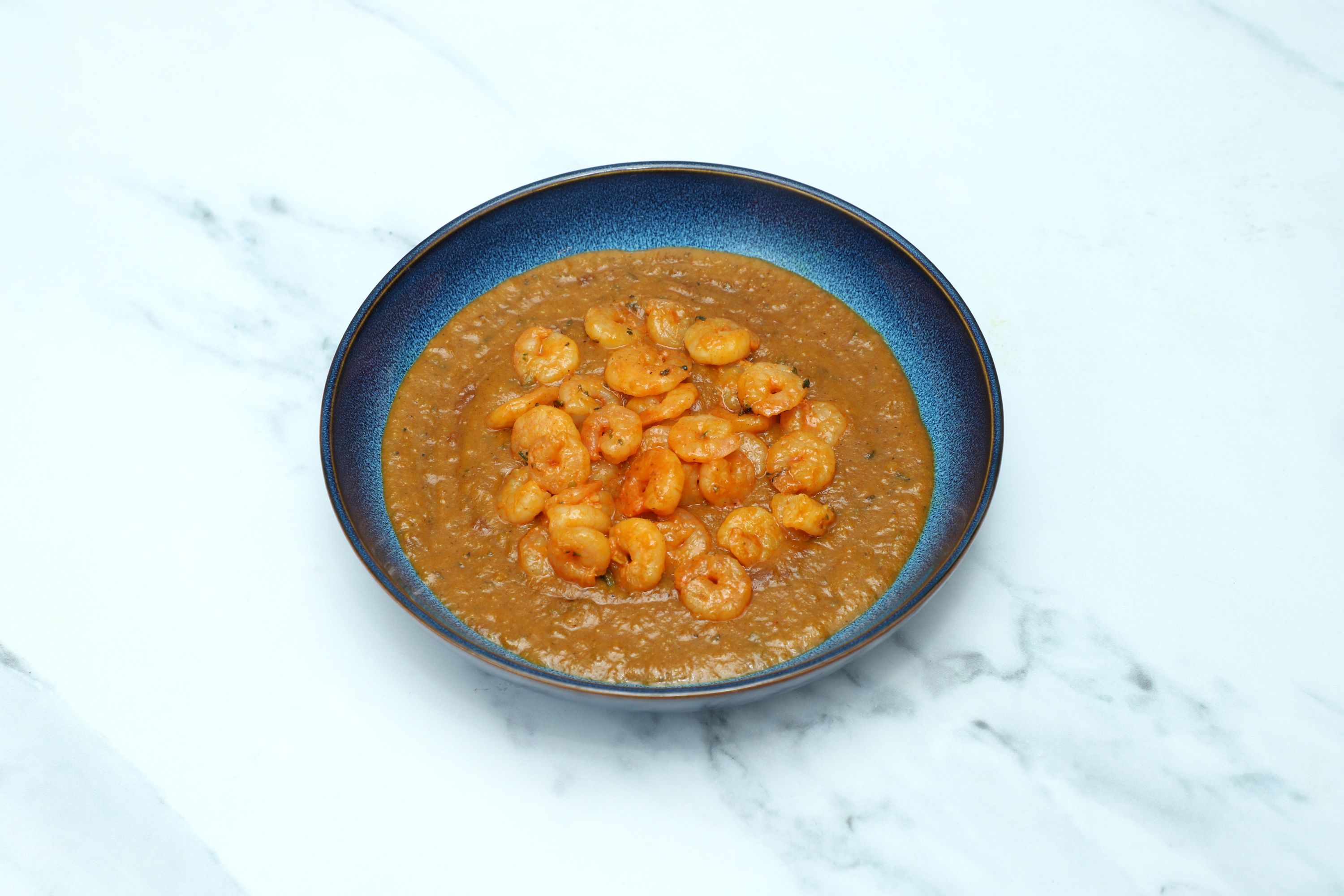 King Prawn Kadai in a blue serving bowl on a white and grey marble surface.