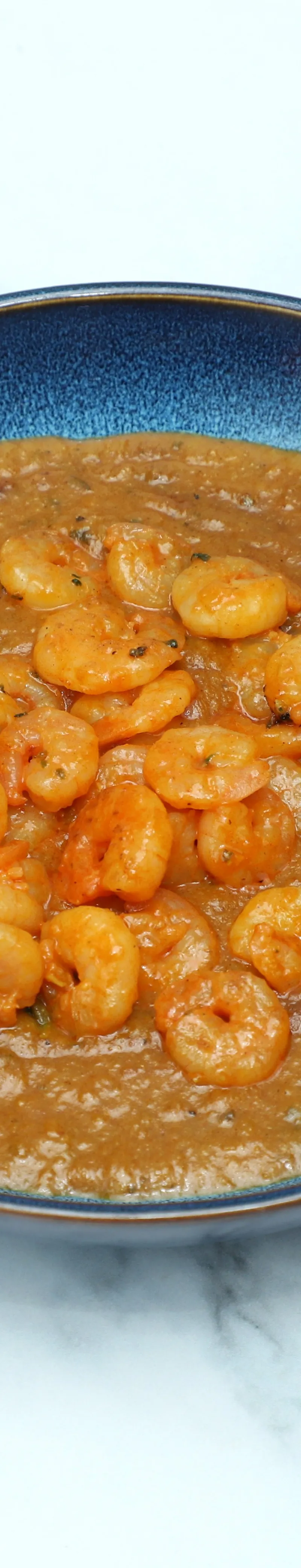 King Prawn Kadai in a blue serving bowl on a white and grey marble surface.