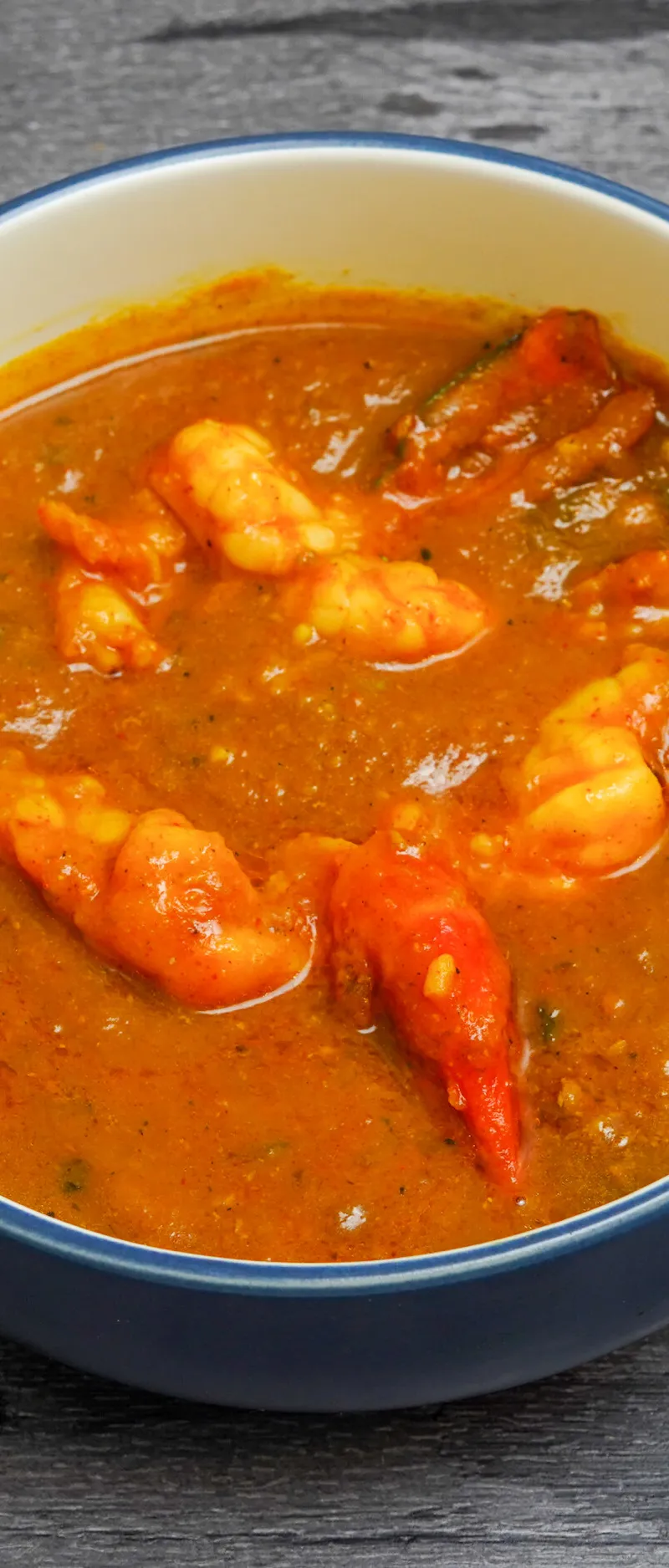 Shrimp curry in a blue and white ceramic bowl on a grey wooden surface