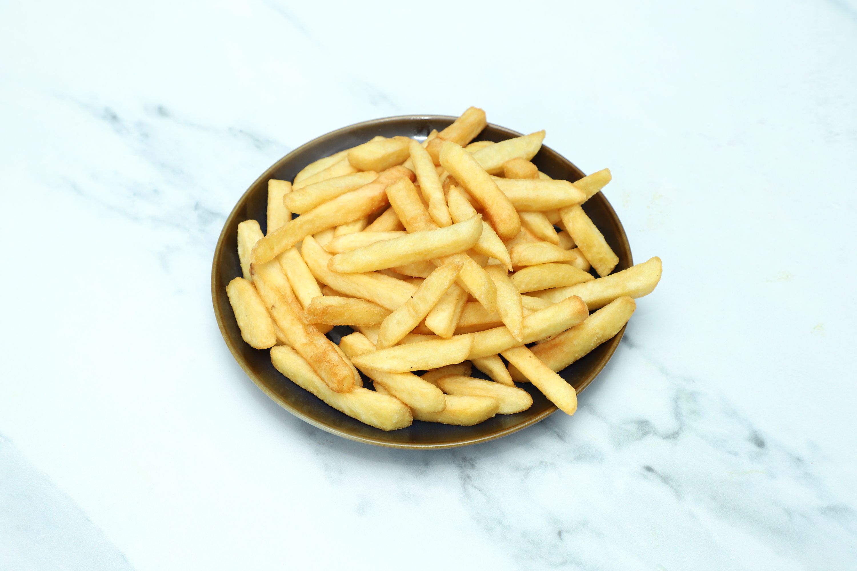 A round brown plate filled with golden crispy French fries resting on a white marble surface.
